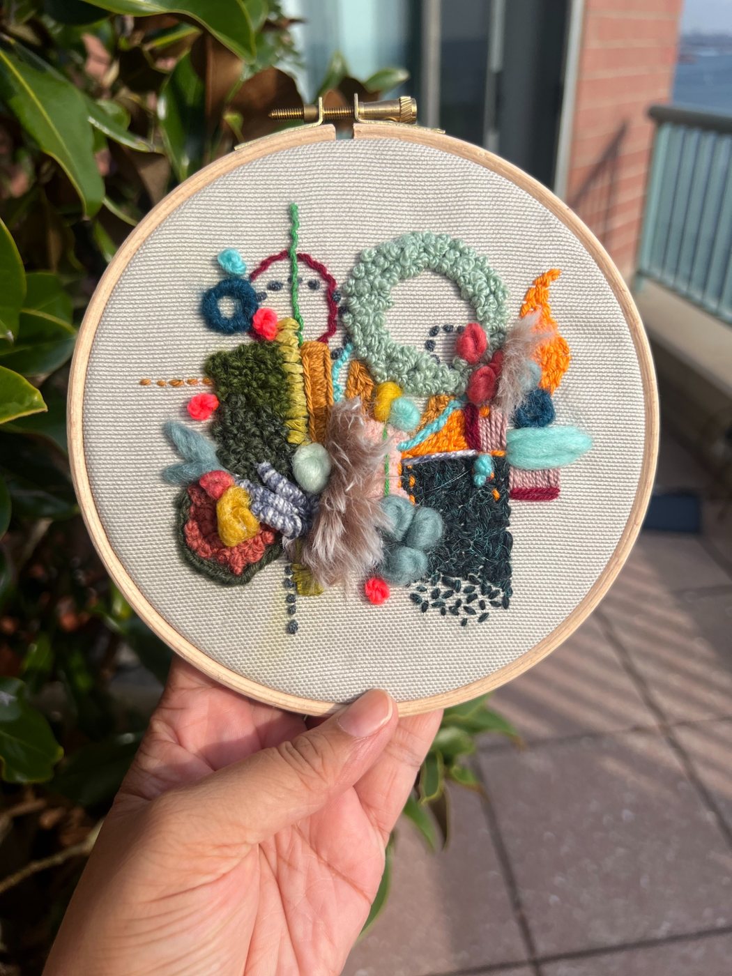 Abstract embroidery in a wooden hoop, stitched with wool, yarn, and thread